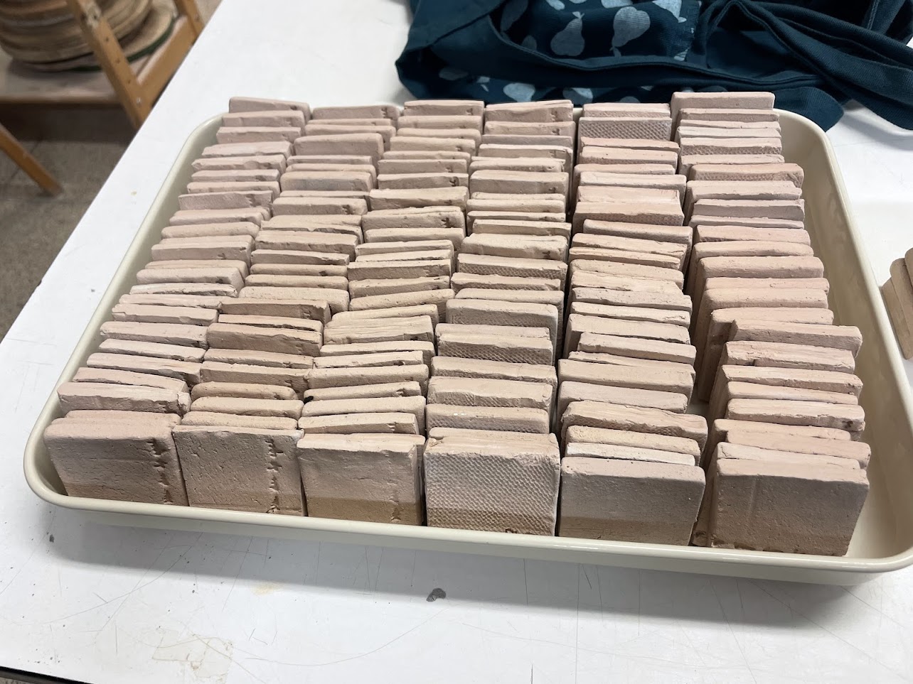 A tray of bisque-fired reclaimed and white clay test tiles, ready to be glazed.