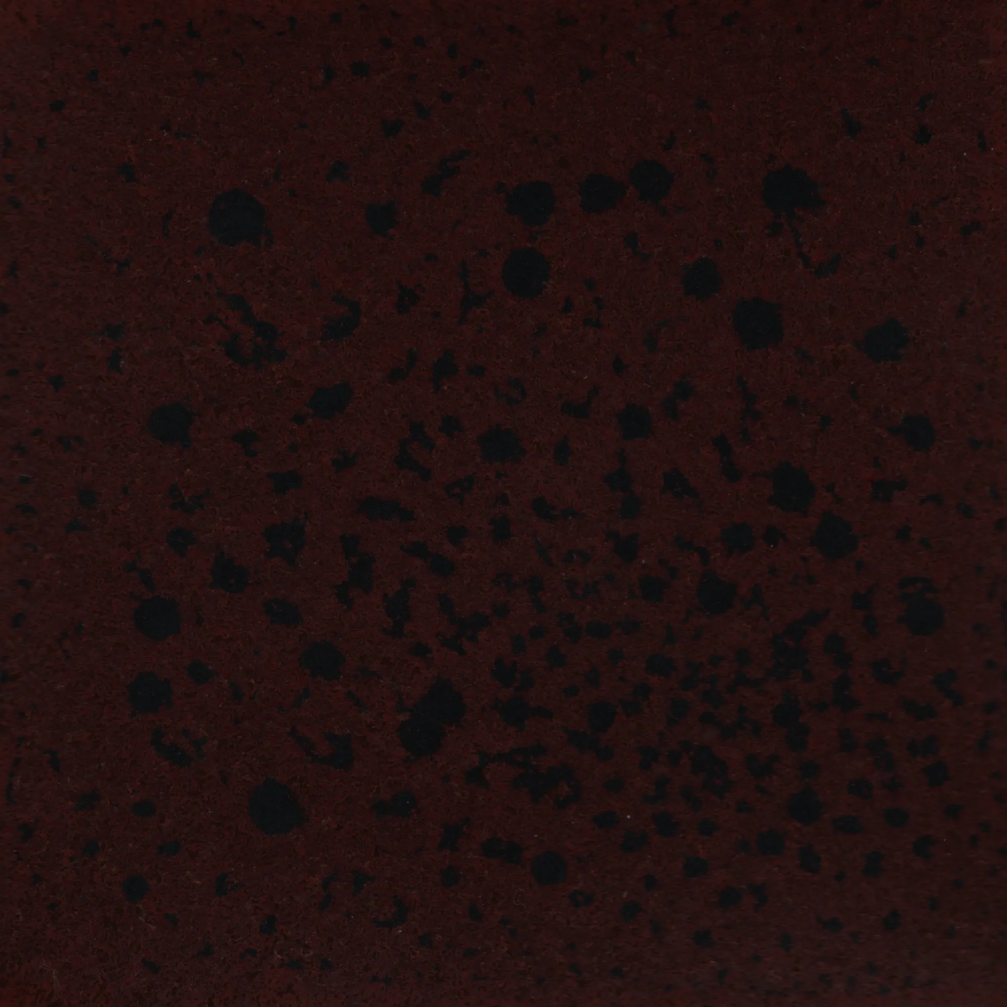 Black speckles across a red background.