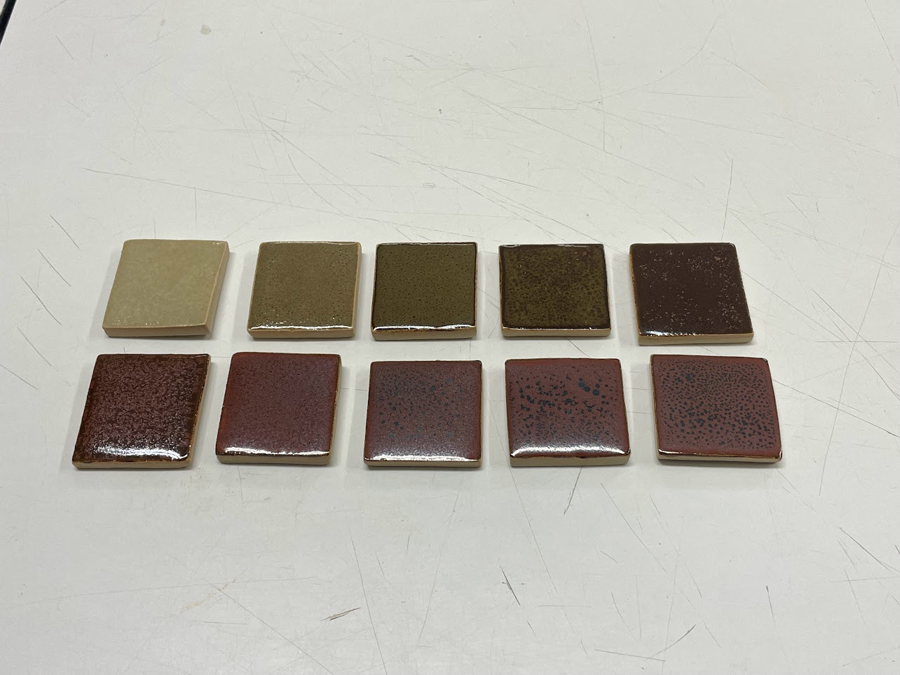 Same tiles after firing, ranging from green to speckled red.