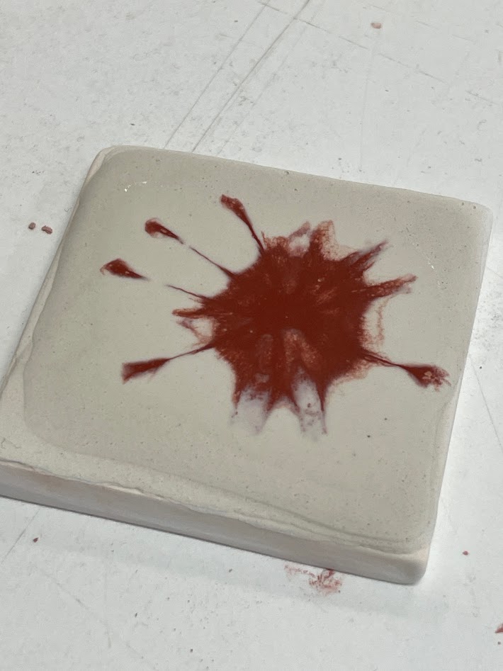 Glaze with red iron oxide splattered onto the base glaze without red iron oxide, before firing.
